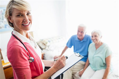 simsearch:6109-08538302,k - Nurse writing on clipboard and senior couple sitting on a bed Stock Photo - Premium Royalty-Free, Code: 6109-08538293