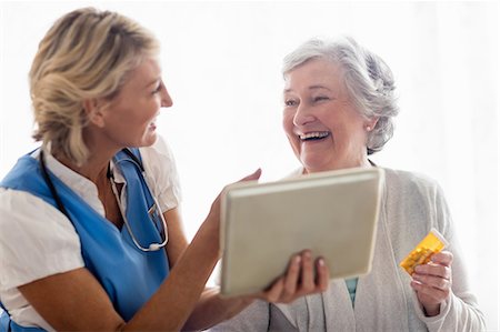 elderly helping elderly pictures - Nurse showing a tablet to a senior woman Stock Photo - Premium Royalty-Free, Code: 6109-08538482