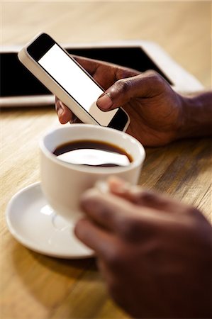 simsearch:6109-08689749,k - Hand using smartphone while taking a cup of coffee in the restaurant Photographie de stock - Premium Libres de Droits, Code: 6109-08689546