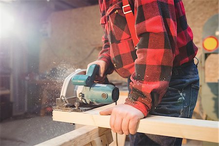 Carpenter sawing a plank of wood in carpentry Stock Photo - Premium Royalty-Free, Code: 6109-08689587