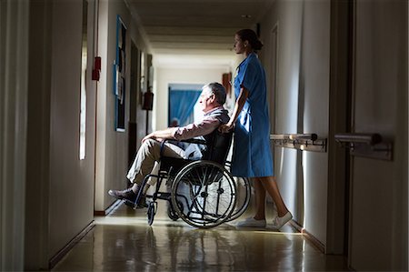 simsearch:6109-06004698,k - Patient in a wheelchair pushing by a nurse in hospital corridor Stock Photo - Premium Royalty-Free, Code: 6109-08689521