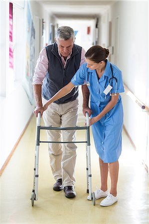 simsearch:6109-08689528,k - Nurse helping senior patient to walk with walking frame in hospital corridor Stock Photo - Premium Royalty-Free, Code: 6109-08689525