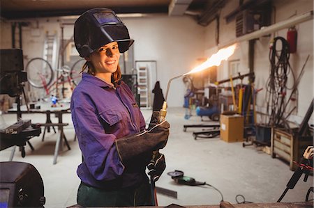 simsearch:6109-08689646,k - A portrait of a young woman welder with a flaming torch Stock Photo - Premium Royalty-Free, Code: 6109-08689645