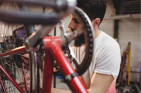 simsearch:6109-08689682,k - Hipster repairing a bicycle in a workshop Stock Photo - Premium Royalty-Free, Code: 6109-08689667