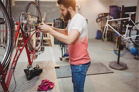 simsearch:6109-08689682,k - Hipster repairing a bicycle in a workshop Stock Photo - Premium Royalty-Free, Code: 6109-08689665