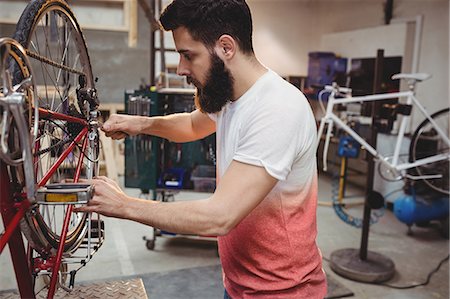 simsearch:6109-08689682,k - Hipster repairing a bicycle in a workshop Stock Photo - Premium Royalty-Free, Code: 6109-08689666