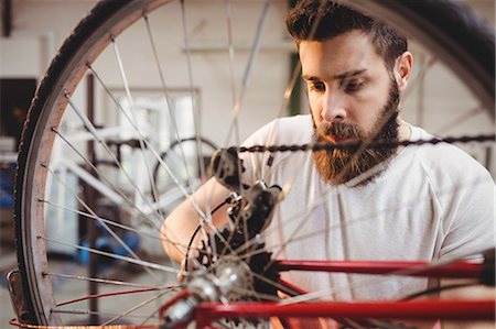 simsearch:6109-08689682,k - Portrait of hipster repairing a bicycle in a workshop Stock Photo - Premium Royalty-Free, Code: 6109-08689668
