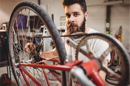 simsearch:6109-08689682,k - Portrait of hipster repairing a bicycle in a workshop Stock Photo - Premium Royalty-Free, Code: 6109-08689669