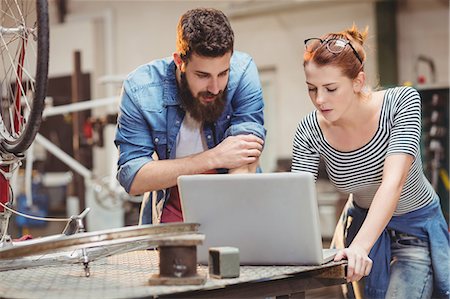 simsearch:6109-08689682,k - Bicycle repairer colleagues looking at laptop in a bicycle work shop Stock Photo - Premium Royalty-Free, Code: 6109-08689673