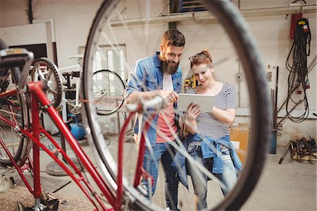 simsearch:6109-08689682,k - Bicycle repairer colleagues looking at laptop in a bicycle work shop Stock Photo - Premium Royalty-Free, Code: 6109-08689671