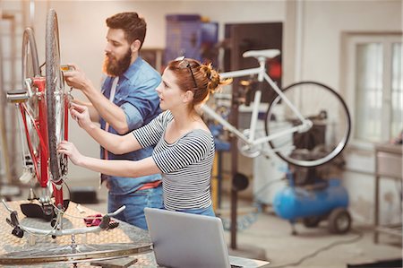 simsearch:6109-08689682,k - Duo of colleague repairing a bicycle in a workshop Stock Photo - Premium Royalty-Free, Code: 6109-08689676