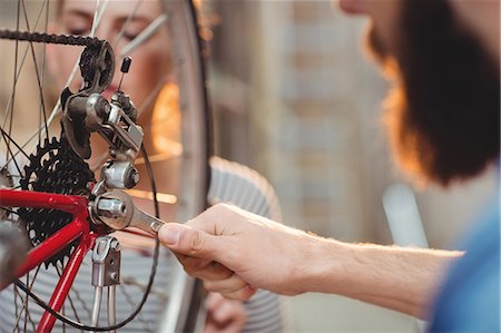 simsearch:6109-08689682,k - Close-up of a hipster repairing a bicycle wheel in a workshop Stock Photo - Premium Royalty-Free, Code: 6109-08689678