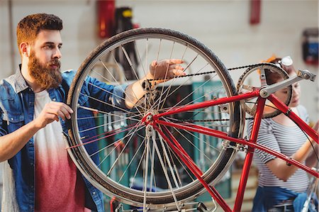 simsearch:6109-08689682,k - Colleague repairing a bicycle in a workshop Stock Photo - Premium Royalty-Free, Code: 6109-08689682