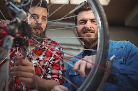 simsearch:6109-08537332,k - Low angle view of two mechanics repairing a bicycle wheel in their workshop Stock Photo - Premium Royalty-Free, Code: 6109-08689895