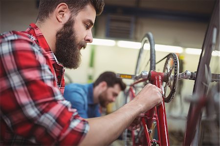 simsearch:6109-08537332,k - Focus on foreground of mechanic repairing a bicycle in his workshop Stock Photo - Premium Royalty-Free, Code: 6109-08689898