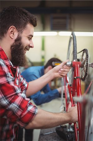 simsearch:6109-08537332,k - Profile view of mechanic repairing a bicycle in his workshop Stock Photo - Premium Royalty-Free, Code: 6109-08689899