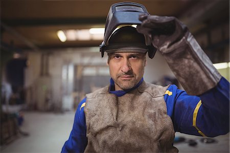 Worker touching helmet in the workshop Stock Photo - Premium Royalty-Free, Code: 6109-08689979