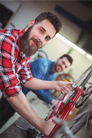 simsearch:6109-08537332,k - Portrait of mechanic repairing a bicycle in his workshop Stock Photo - Premium Royalty-Free, Code: 6109-08689900