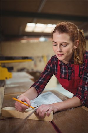 Female carpenter marking on wooden plank with pencil in workshop Stock Photo - Premium Royalty-Free, Code: 6109-08689905