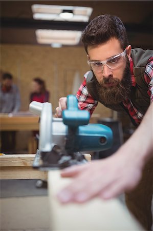 simsearch:6109-08538063,k - Confident carpenter using a jigsaw in workshop Foto de stock - Sin royalties Premium, Código: 6109-08689914