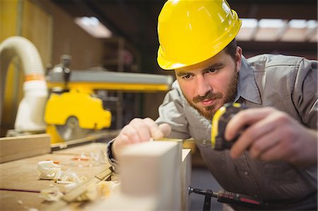 simsearch:6109-08538159,k - Carpenter measuring length of wooden plank with measuring tape in workshop Photographie de stock - Premium Libres de Droits, Code: 6109-08689922