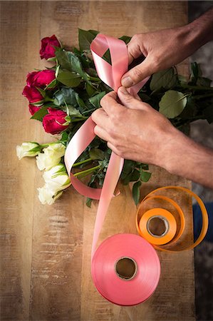 florist (männlich) - Close-up of male florist tying poly ribbon on bouquet of flower at his flower shop Stockbilder - Premium RF Lizenzfrei, Bildnummer: 6109-08690150