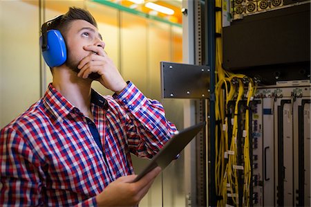 simsearch:6109-08690053,k - Technician in head phones using digital tablet while analyzing server in server room Stock Photo - Premium Royalty-Free, Code: 6109-08690122