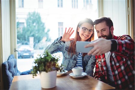 simsearch:6109-08690396,k - Cheerful young couple video chatting at cafe Stock Photo - Premium Royalty-Free, Code: 6109-08690383