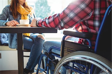 simsearch:6109-08690396,k - Midsection of disabled man sitting with woman while having coffee at cafe Stock Photo - Premium Royalty-Free, Code: 6109-08690396