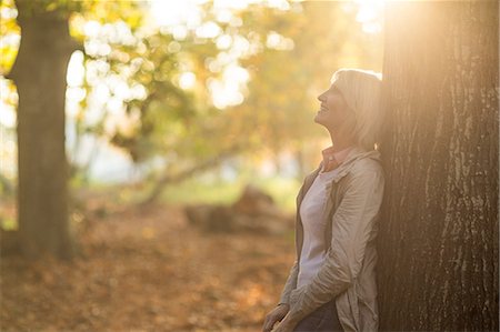 Side view of mature woman leaning on tree in forest Stock Photo - Premium Royalty-Free, Code: 6109-08690496