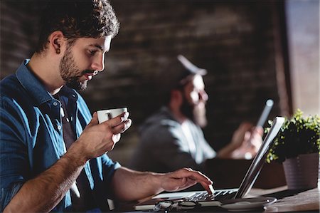 fashion food - Side view of young man drinking fresh coffee while working on laptop at cafe Stock Photo - Premium Royalty-Free, Code: 6109-08690412