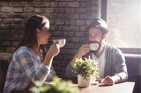 simsearch:6109-08690396,k - Young friends drinking coffee while sitting at cafe Stock Photo - Premium Royalty-Free, Code: 6109-08690417