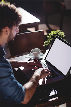 pc store - High angle view of young male customer typing on laptop at cafe Stock Photo - Premium Royalty-Free, Code: 6109-08690414