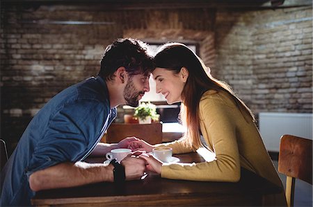 romantic couple cafe - Side view of young happy couple holding hands at cafe Stock Photo - Premium Royalty-Free, Code: 6109-08690421