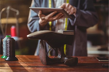 Shoemaker using digital tablet in workshop Stock Photo - Premium Royalty-Free, Code: 6109-08763847