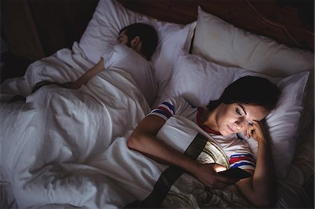 Woman using mobile phone while lying on bed at bedroom Foto de stock - Sin royalties Premium, Código: 6109-08763895