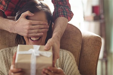 simsearch:6109-08763931,k - Man surprising woman with a gift in the living room at home Stock Photo - Premium Royalty-Free, Code: 6109-08763943