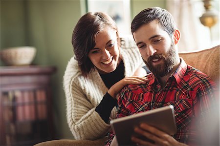 simsearch:6109-08763934,k - Couple using digital tablet in living room at home Stock Photo - Premium Royalty-Free, Code: 6109-08763940