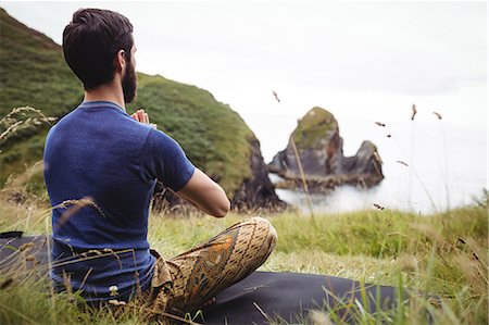 Rear view of man performing yoga on cliff Stock Photo - Premium Royalty-Free, Code: 6109-08763945