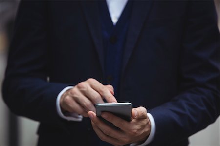 dialing - Mid section of businessman using mobile phone Stock Photo - Premium Royalty-Free, Code: 6109-08763977