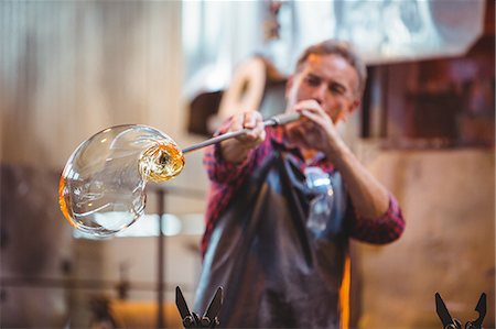 simsearch:693-05794393,k - Glassblower shaping a glass on the blowpipe at glassblowing factory Stock Photo - Premium Royalty-Free, Code: 6109-08764068