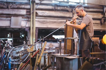 Glassblower shaping a glass on the blowpipe at glassblowing factory Stock Photo - Premium Royalty-Free, Code: 6109-08764077