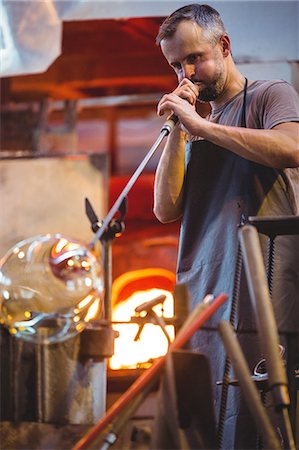 simsearch:6109-08764042,k - Glassblower shaping a glass on the blowpipe at glassblowing factory Stock Photo - Premium Royalty-Free, Code: 6109-08764075