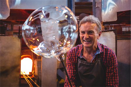 senior adult workshop - Portrait of glassblower shaping a glass on the blowpipe at glassblowing factory Stock Photo - Premium Royalty-Free, Code: 6109-08764087