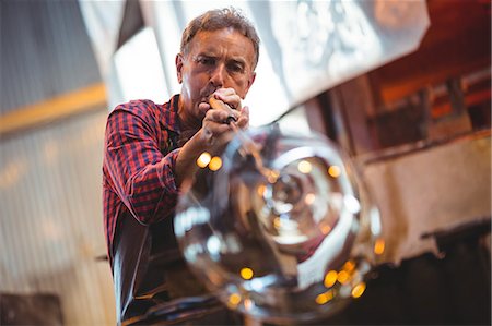 senior adult workshop - Glassblower shaping a glass on the blowpipe at glassblowing factory Stock Photo - Premium Royalty-Free, Code: 6109-08764096