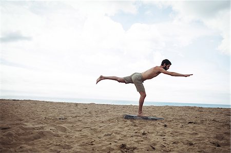 simsearch:6109-08830642,k - Man performing stretching exercise on beach Stock Photo - Premium Royalty-Free, Code: 6109-08764022