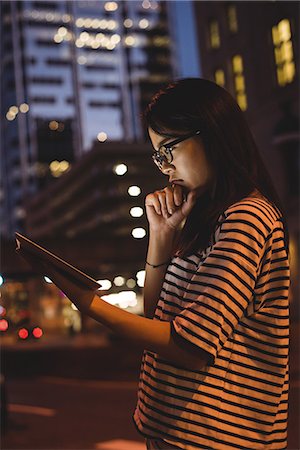 simsearch:632-08993608,k - Thoughtful young woman using digital tablet on street at night Stock Photo - Premium Royalty-Free, Code: 6109-08764132