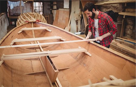 Man preparing wooden boat frame in boatyard Stock Photo - Premium Royalty-Free, Code: 6109-08764345