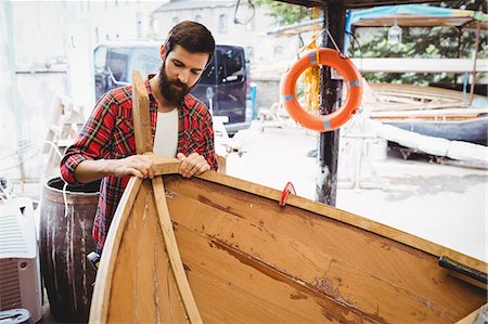 simsearch:6109-08764384,k - Man preparing wooden boat frame in boatyard Foto de stock - Sin royalties Premium, Código: 6109-08764350
