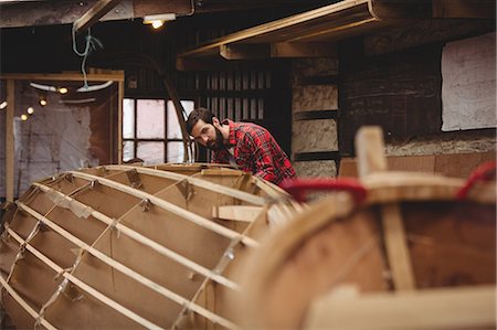 Man preparing wooden boat frame in boatyard Stock Photo - Premium Royalty-Free, Code: 6109-08764364